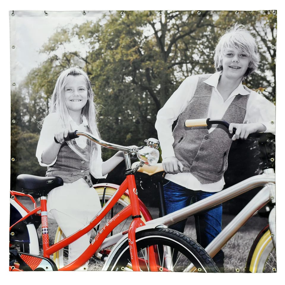 Vierkant frontlit-spandoek met een zwart-witfoto van twee kinderen met rode fietsen, ringen rondom
