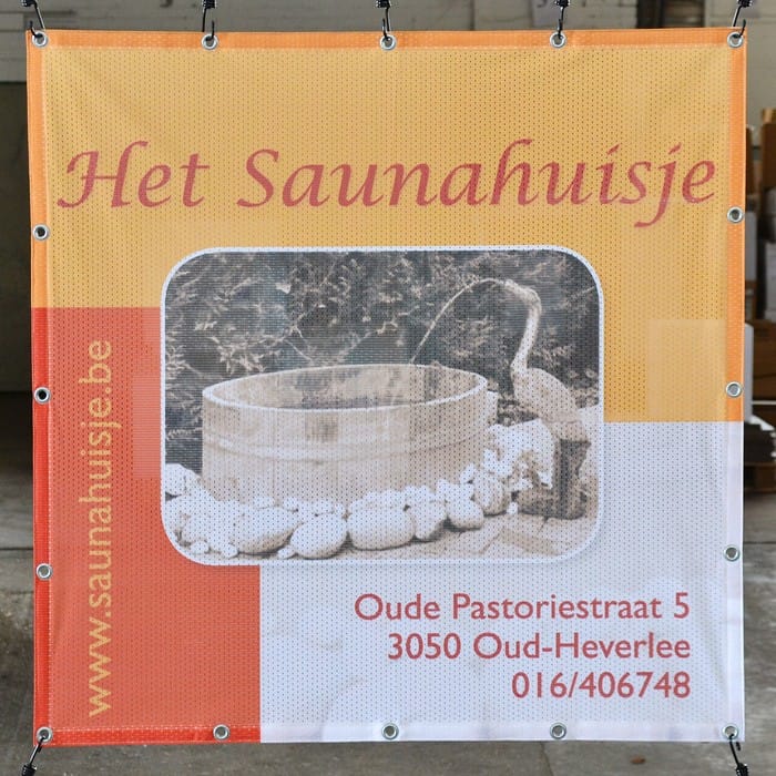 Bedrukt polymesh-spandoek met ringen, aan haken opgehangen in een werkplaats