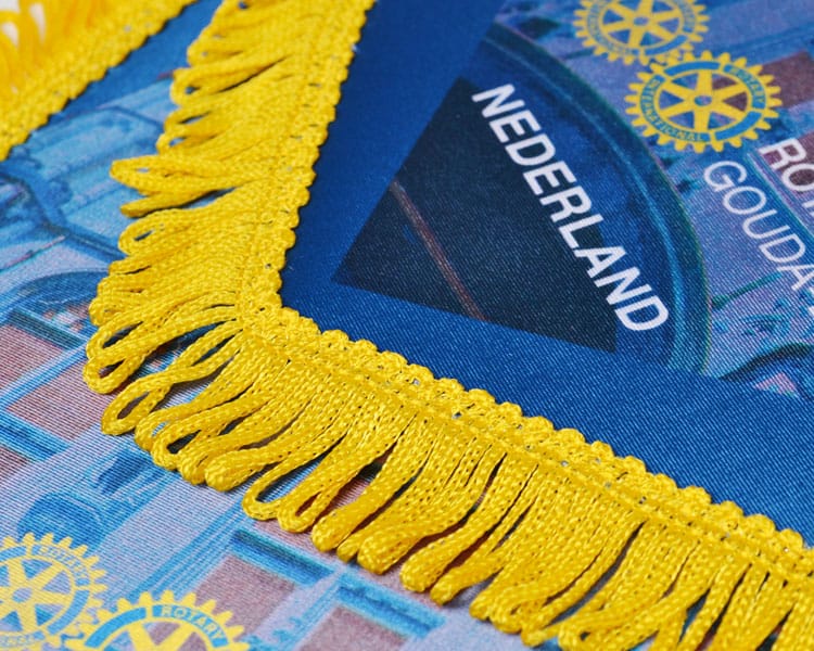 Close-up van een vaantje met gouden franjerand langs de bedrukte stof