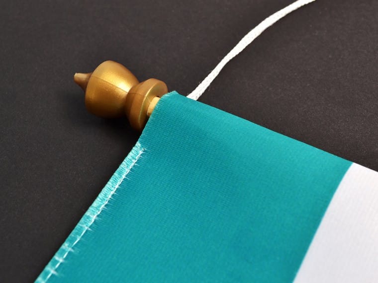 Detail van een vaantje: gestikte zoom om het stokje met gouden knop