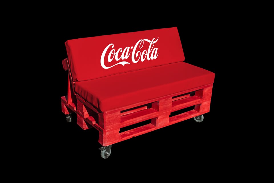 Rode palletbank op wieltjes met kussens, de rugleuning bedrukt met een merklogo