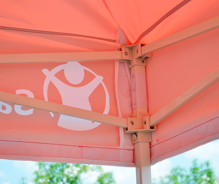 Onderkant van een rood bedrukt tentdak met het frame en de hoekverbindingen zichtbaar