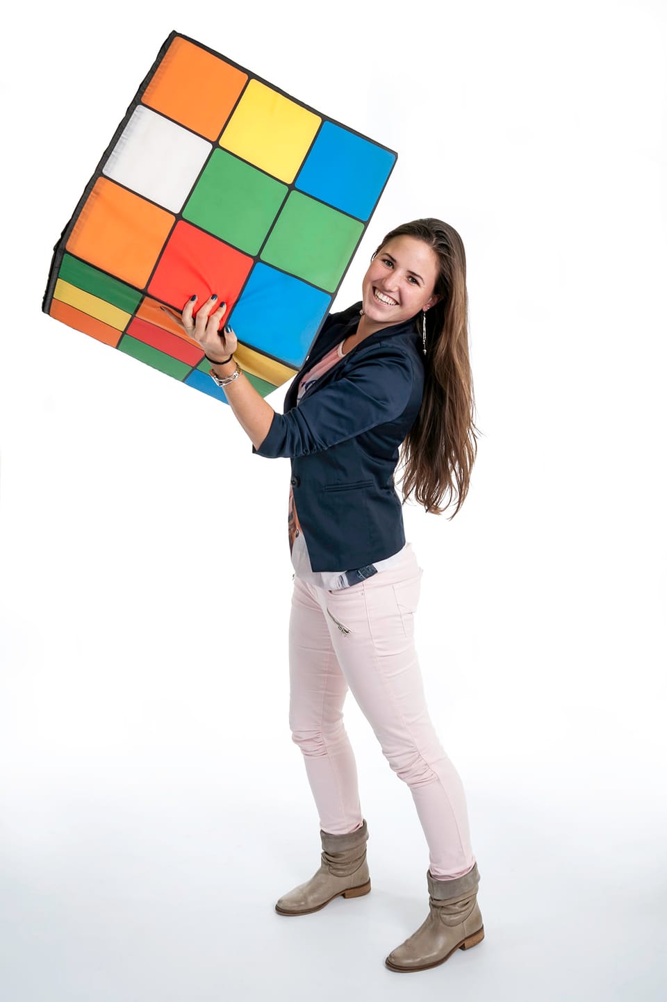 Vrouw tilt een grote poef op die bedrukt is als kleurige puzzelkubus