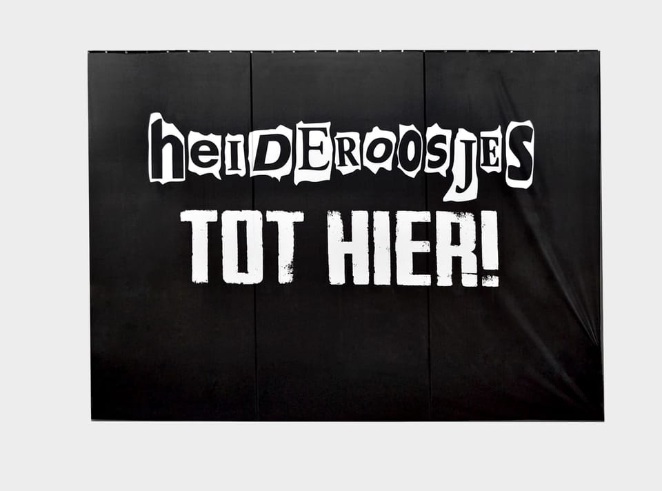 Zwarte backdrop met witte bandtekst, opgehangen als podiumachterdoek