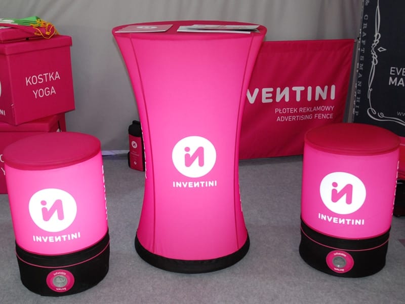 Roze opblaasbare statafel en twee hockers met logo in een beursstand