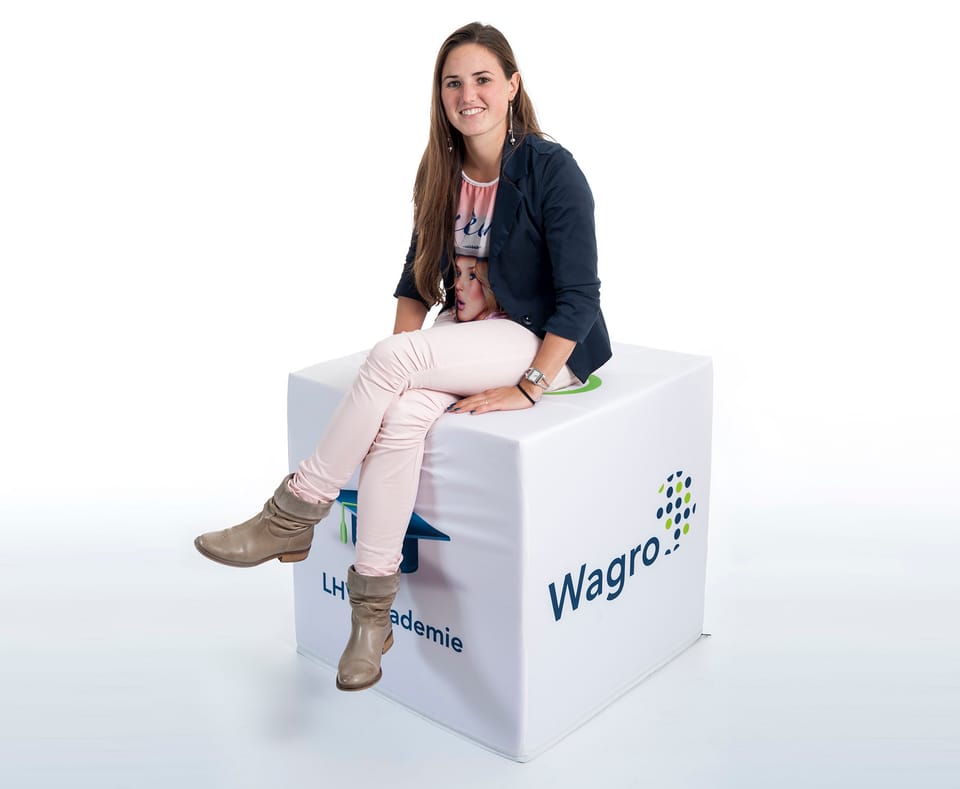 Vrouw zit op een grote witte poef met logo's op de zijkanten
